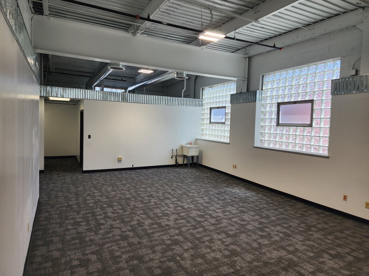 Interior of a private office at Incubator Alley — fresh paint, new carpet, glass-block windows, exposed ceiling